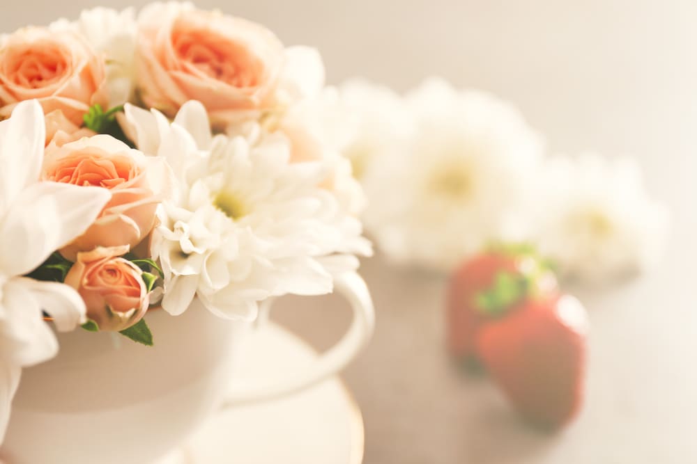 Delicate photo of white chrysanthemums and pink rose flowers against a background of strawberries.